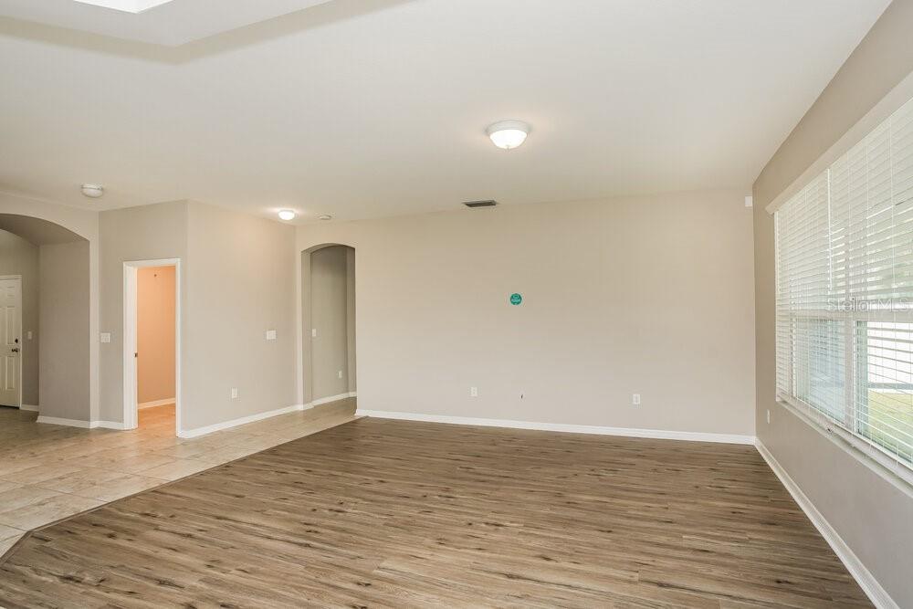 An empty living room features light-colored walls, wood-look flooring, and a large window — 9039 41ST STREET E, PARRISH, FL