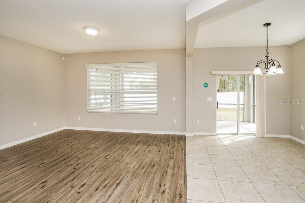 An open-concept room features wood-look flooring, tile, a large window, and a sliding glass door — 9039 41ST STREET E, PARRISH, FL