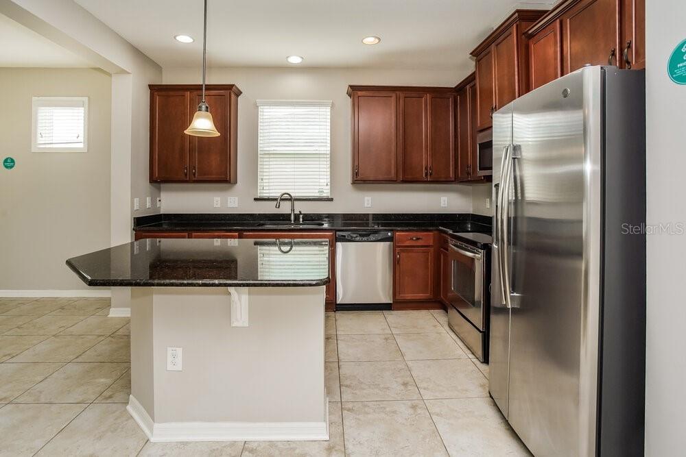 A kitchen with dark wood cabinets, granite countertops, stainless steel appliances, and tile flooring — 9039 41ST STREET E, PARRISH, FL