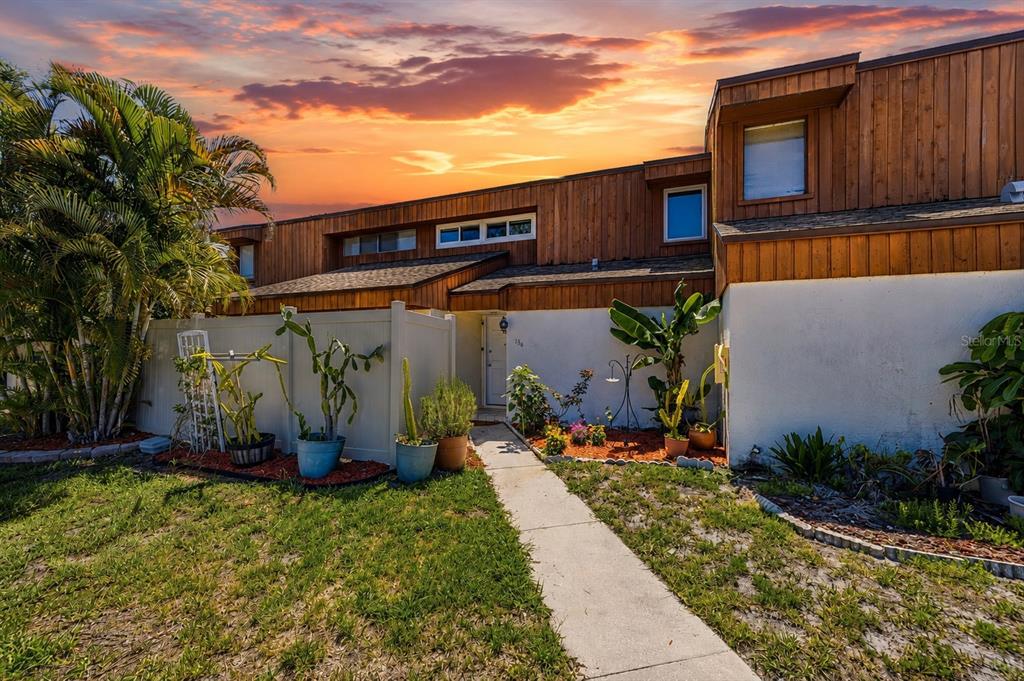 A two-story townhouse with wood siding and a white stucco lower level at sunset — 2074 SUNSET POINT ROAD UNIT 136, CLEARWATER, FL