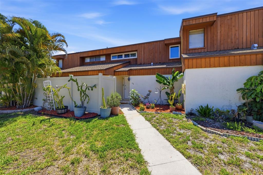 A two-story townhouse exterior with wood siding, a white stucco lower level, and a walkway — 2074 SUNSET POINT ROAD UNIT 136, CLEARWATER, FL
