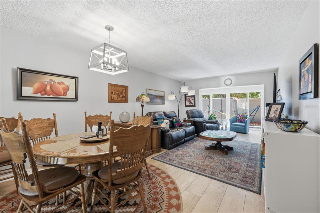 A living and dining room with wood floors, a round table, and a leather sofa — 2074 SUNSET POINT ROAD UNIT 136, CLEARWATER, FL