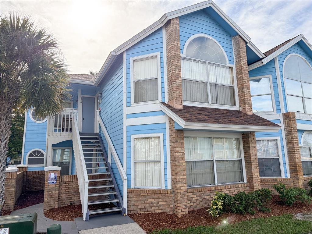 A living room features light blue walls, wood-look flooring, two sofas, a coffee table, and a clock — 2731 N POINCIANA BOULEVARD UNIT 105, KISSIMMEE, FL