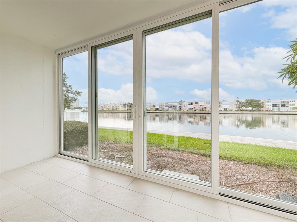 A sunroom with white tile flooring features large sliding glass doors overlooking a waterfront view — 7625 SUN ISLAND DRIVE S UNIT 101, SOUTH PASADENA, FL