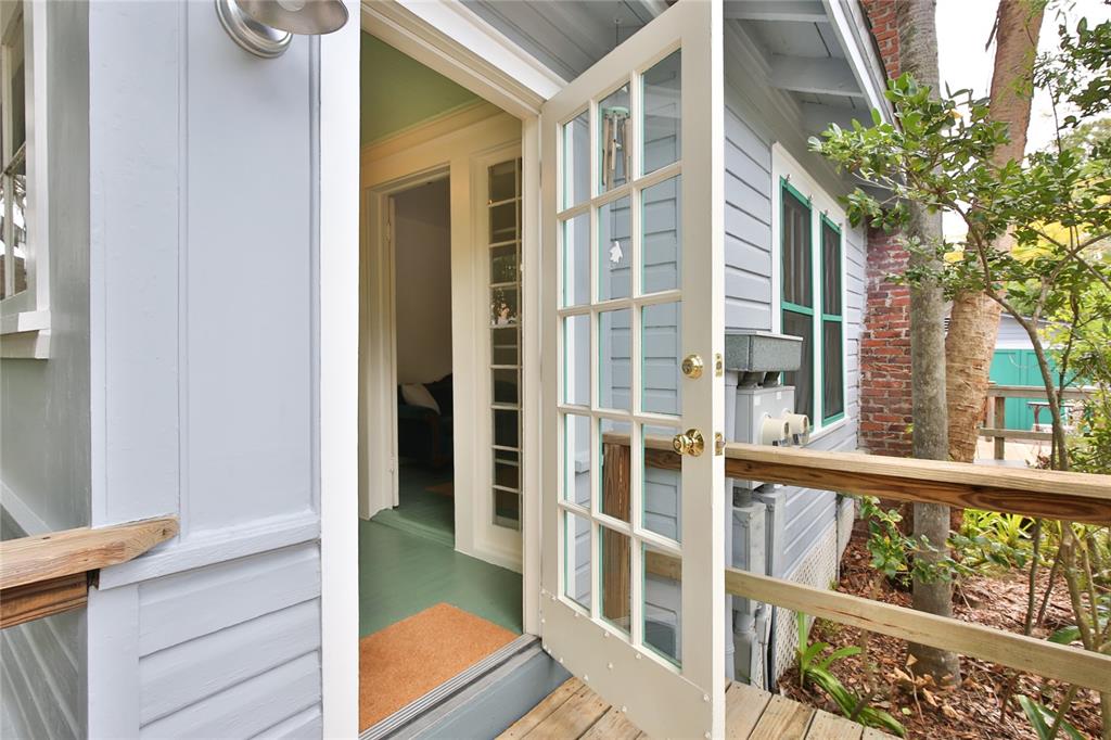 A light blue house exterior features a wooden deck and an open glass-paned door — 708 42ND STREET, SARASOTA, FL