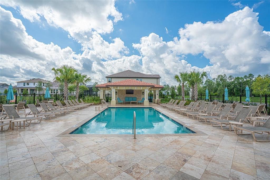 A rectangular swimming pool is surrounded by lounge chairs and a covered patio area — 8224 PROCIDA ISLE LANE, WINDERMERE, FL