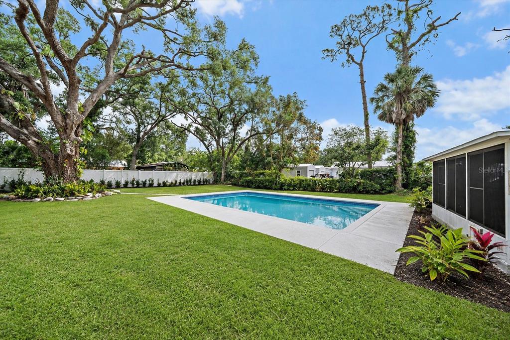 A living room with light wood floors, a red armchair, and an open kitchen area — 2503 53RD AVENUE W, BRADENTON, FL