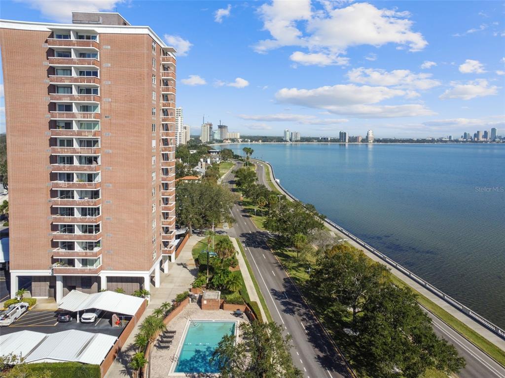 An aerial view shows a tall brick apartment building next to a pool and road — 4015 BAYSHORE BOULEVARD UNIT 7D, TAMPA, FL