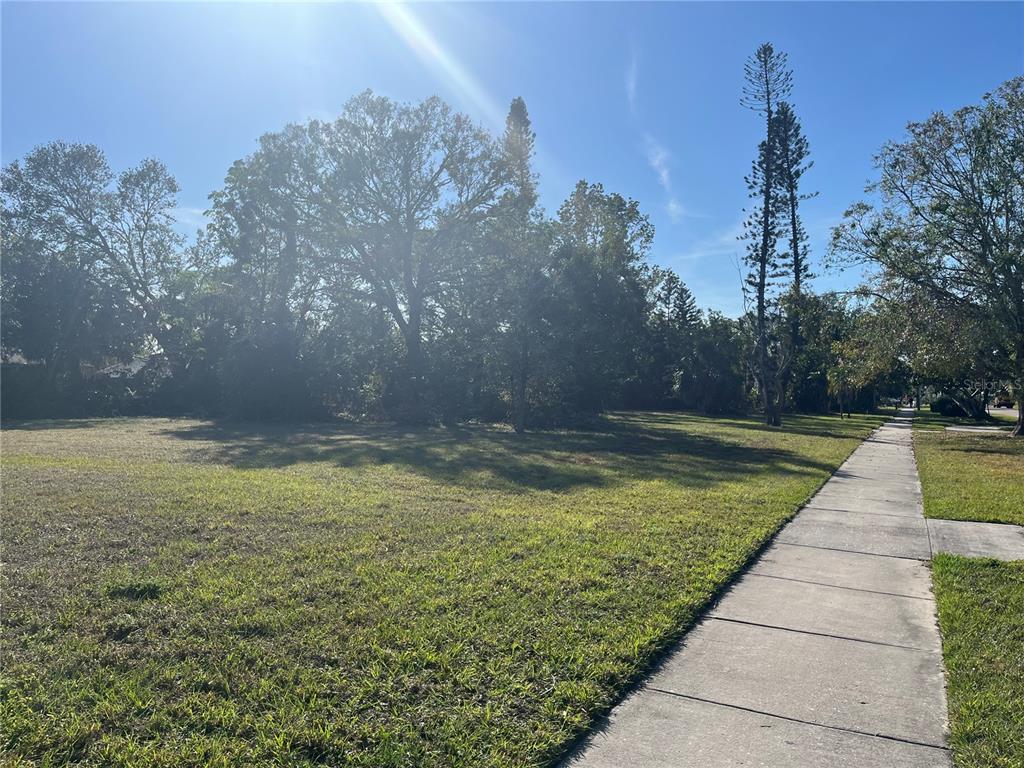 A grassy, vacant residential lot sits beside a concrete sidewalk under a clear blue sky — 2470 RINGLING BOULEVARD, SARASOTA, FL