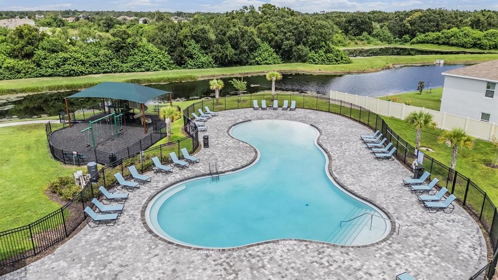 An aerial view shows a swimming pool with a surrounding patio, lounge chairs, and playground — 12175 WATER ASH PLACE, RIVERVIEW, FL