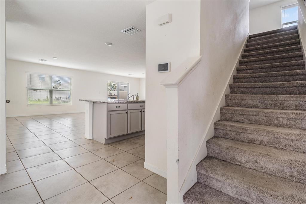 A carpeted staircase leads upstairs next to a kitchen with a granite-topped island — 12175 WATER ASH PLACE, RIVERVIEW, FL