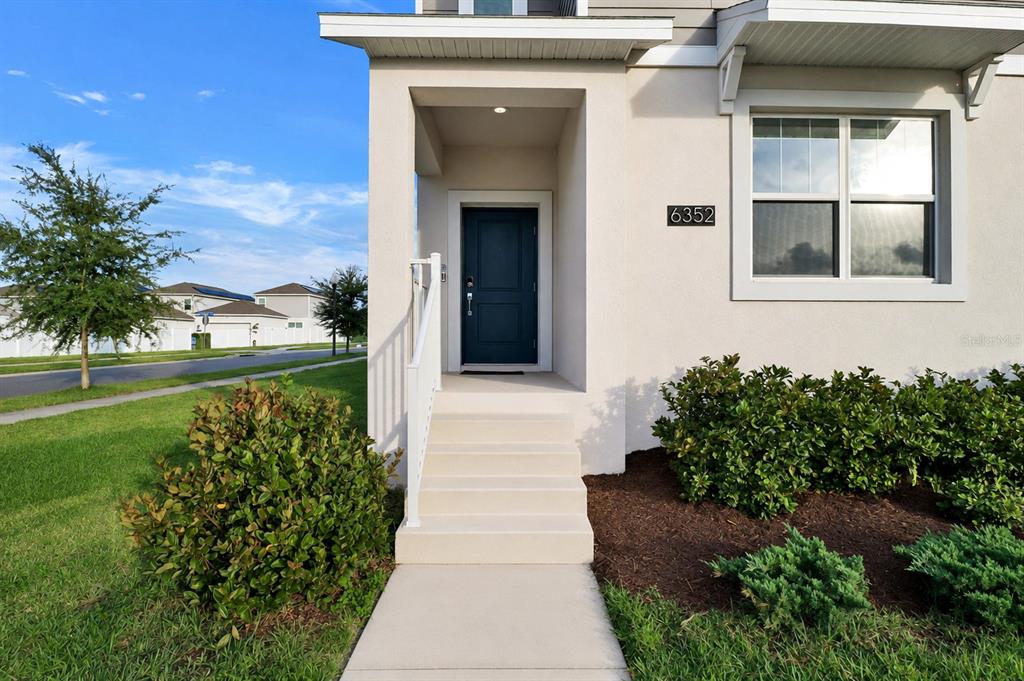 The exterior of a house features a dark blue front door, concrete steps, and landscaping — 6352 SPRUCEPINE LANE, ST CLOUD, FL