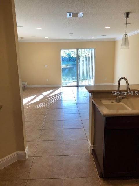 A kitchen sink and counter overlook an open living area with tile floors and sliding doors — 169 CONSTITUTION WAY, WINTER SPRINGS, FL