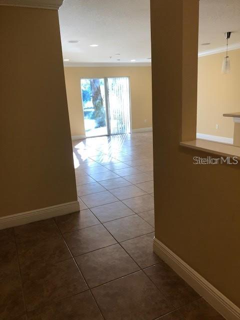 A view through a doorway into a tiled living area with sliding glass doors — 169 CONSTITUTION WAY, WINTER SPRINGS, FL