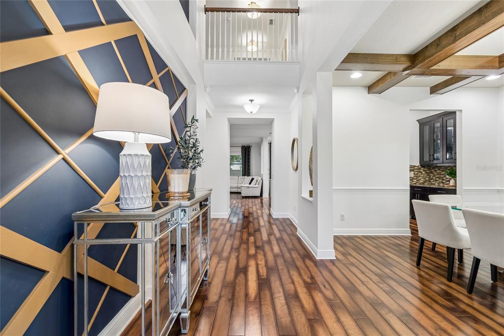 A foyer features a navy accent wall with gold trim, a mirrored console, and wood flooring — 1657 FEATHER GRASS LOOP, LUTZ, FL
