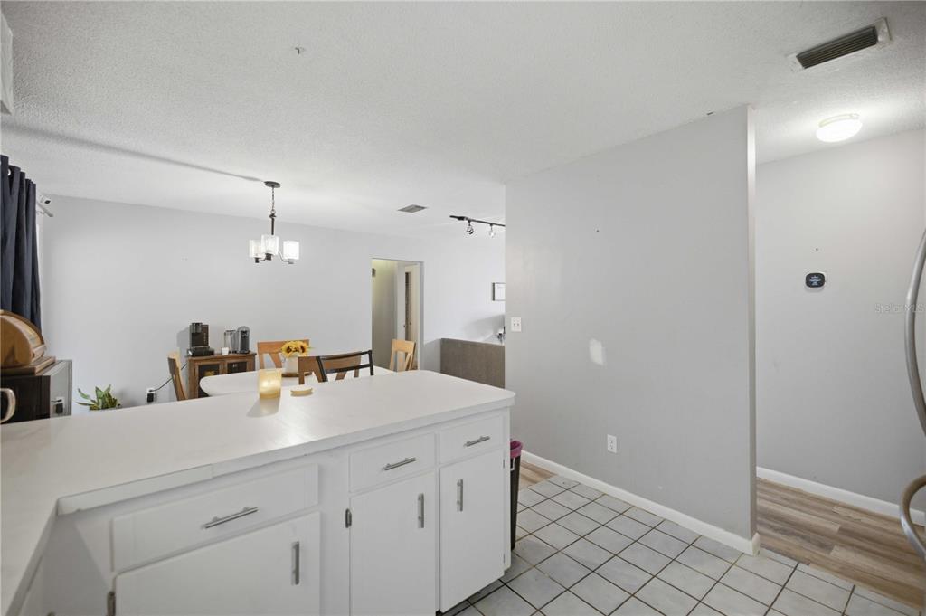 A living room with light wood-look flooring, gray walls, track lighting, and large windows — 477 SPRING LANE, OCALA, FL