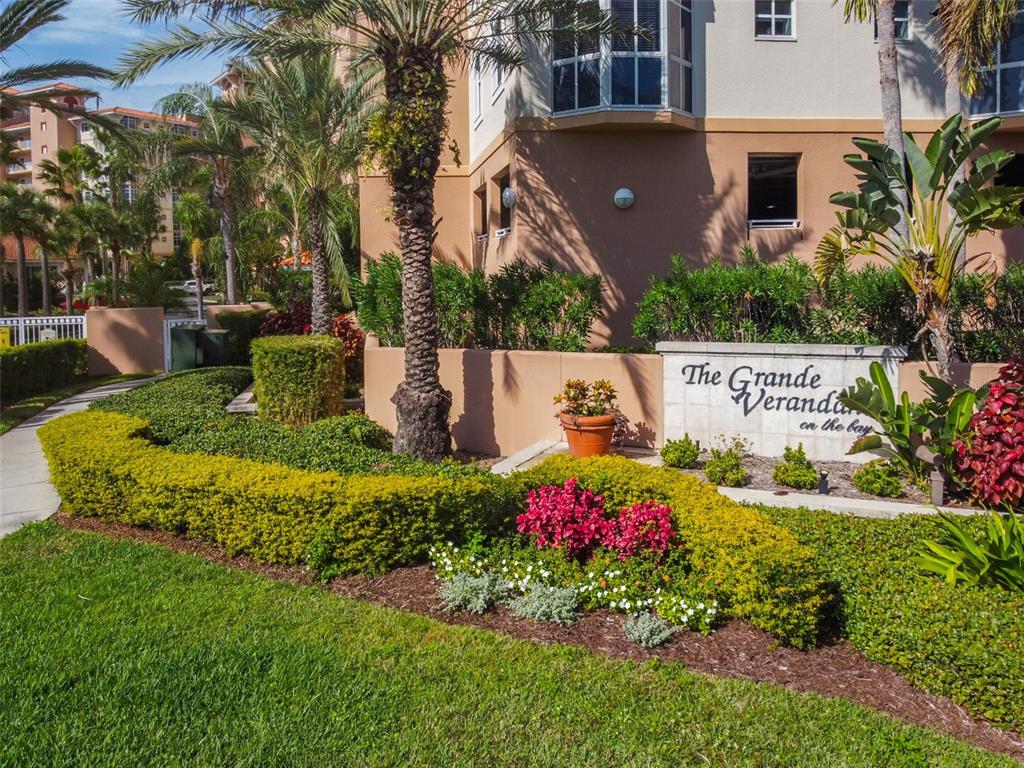 A gated entrance leads to a multi-story apartment building surrounded by palm trees and landscaping — 12033 GANDY BOULEVARD N UNIT 151, ST PETERSBURG, FL