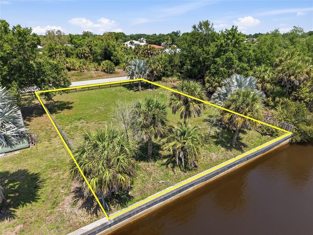 An aerial view shows a vacant, fenced waterfront lot with several palm trees — 28451 SABAL PALM DRIVE, PUNTA GORDA, FL