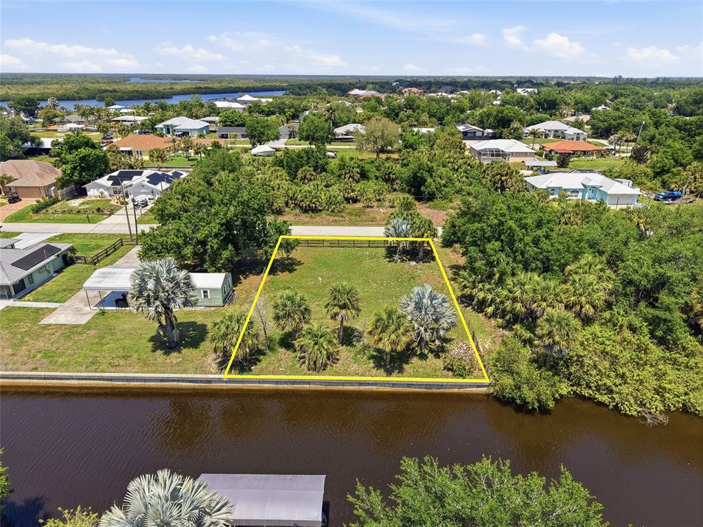 An aerial view shows a vacant, fenced waterfront lot with palm trees and a canal — 28451 SABAL PALM DRIVE, PUNTA GORDA, FL