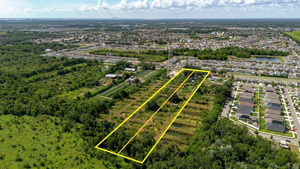 An aerial view shows a long, rectangular plot of land outlined in yellow near suburban homes — 11109 SUMNER ROAD, WIMAUMA, FL