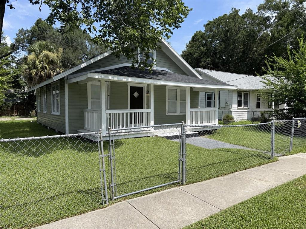 A light green house with a front porch and chain-link fence sits along a sidewalk — 140 KINGSTON AVENUE, DAYTONA BEACH, FL