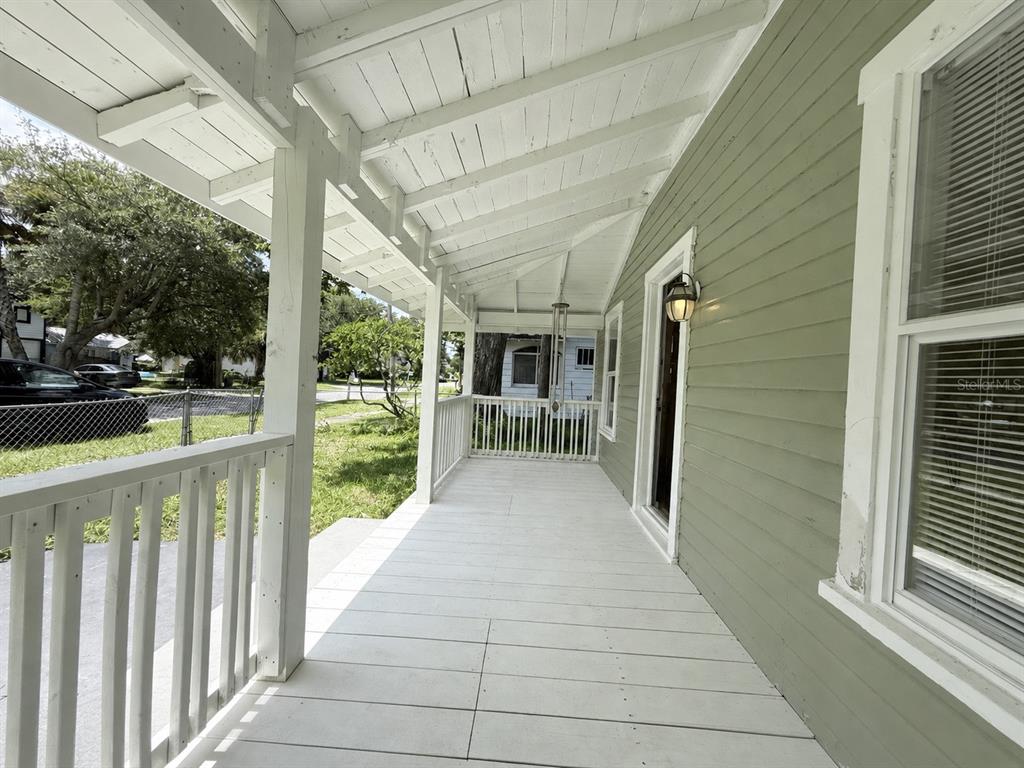 A covered wooden porch with white railings and green siding on the exterior wall — 140 KINGSTON AVENUE, DAYTONA BEACH, FL