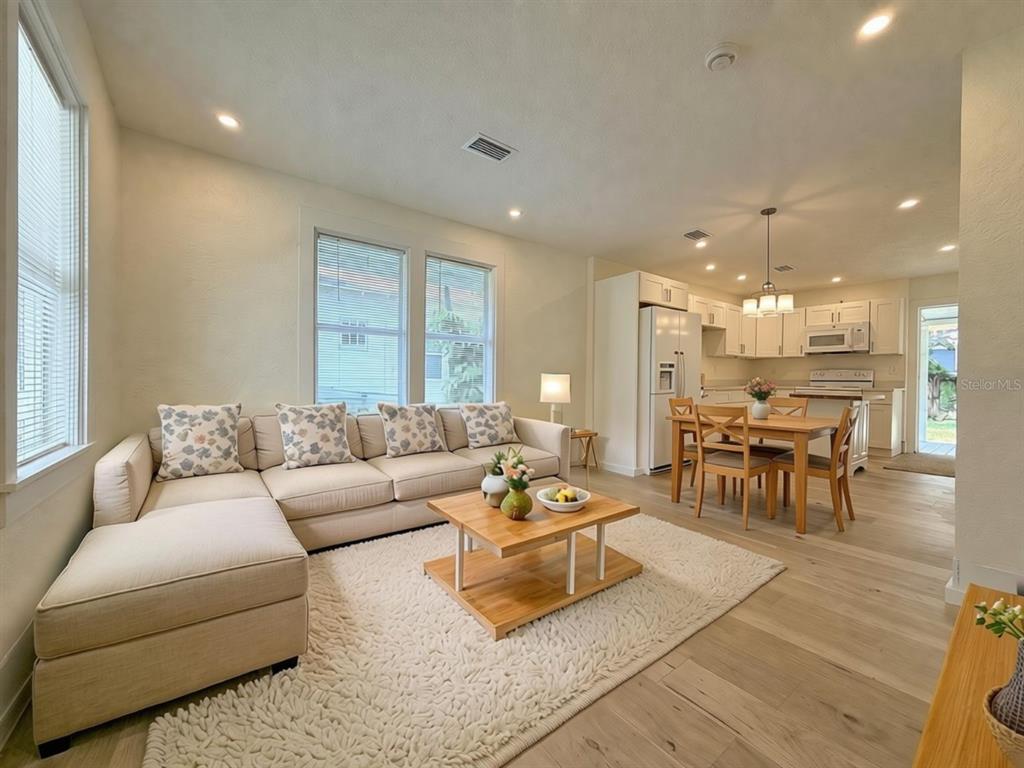 An open-concept living and dining area features light wood flooring, a sectional sofa, and cabinetry — 140 KINGSTON AVENUE, DAYTONA BEACH, FL