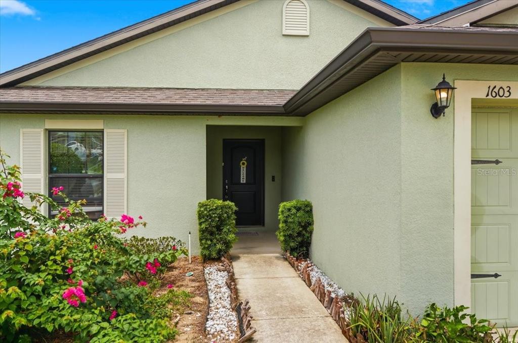 The rear exterior of a single-story house features a covered patio and a grassy yard — 1603 ELLINGTON DRIVE, DUNDEE, FL