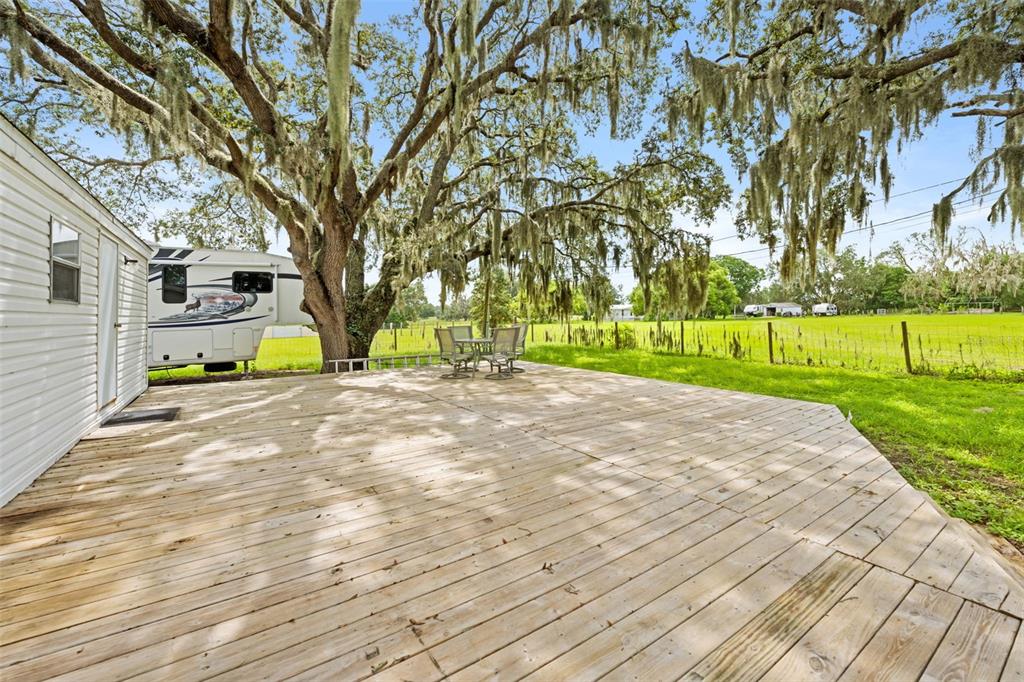 A large wooden deck sits beside a mobile home under a tree with Spanish moss — 4586 CALIFORNIA STREET, BROOKSVILLE, FL
