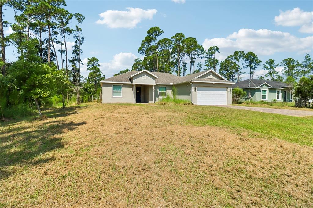 A single-story house with a two-car garage sits on a large, grassy lot — 1730 EAST PKWY, DELAND, FL