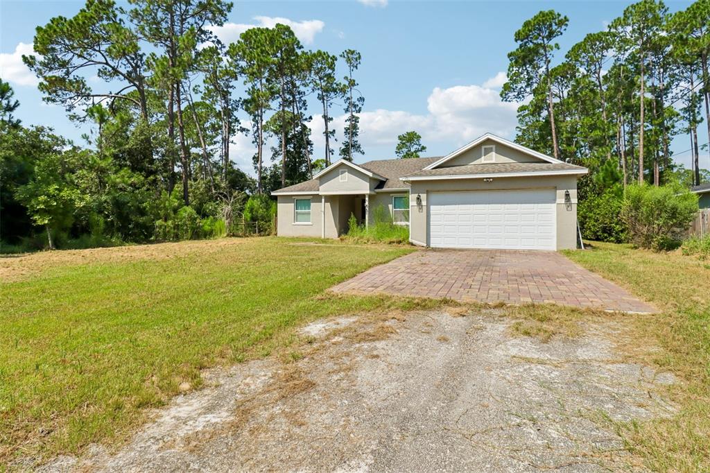 A single-story house with a white garage door and a paved driveway sits on a lot — 1730 EAST PKWY, DELAND, FL
