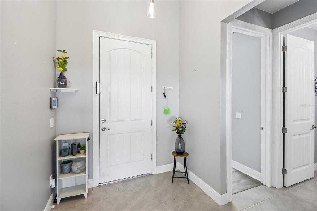 An entryway with light gray walls, tile flooring, a white front door, and two interior doors — 1730 EAST PKWY, DELAND, FL