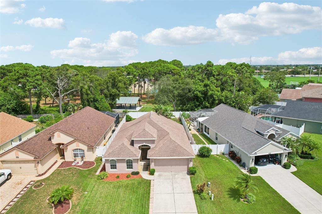 An aerial view shows three suburban houses with brown roofs and green lawns — 2638 BIG PINE DRIVE, HOLIDAY, FL
