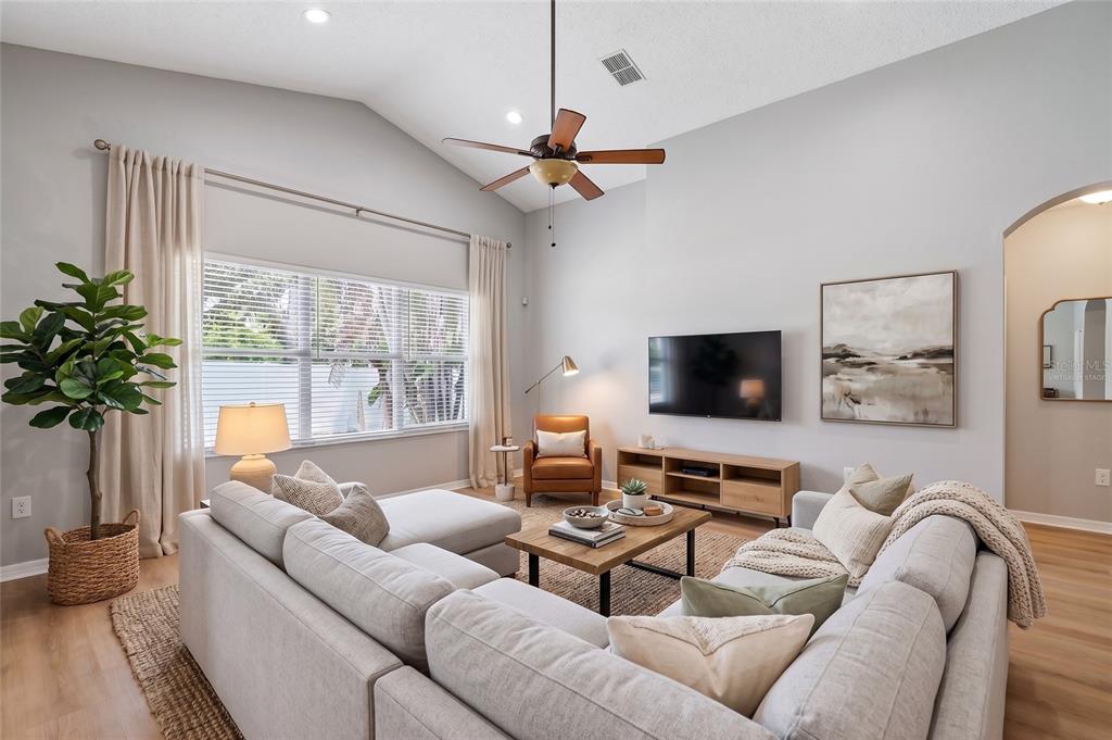 A living room with a vaulted ceiling, wood-look flooring, two leather armchairs, and a sofa — 2638 BIG PINE DRIVE, HOLIDAY, FL