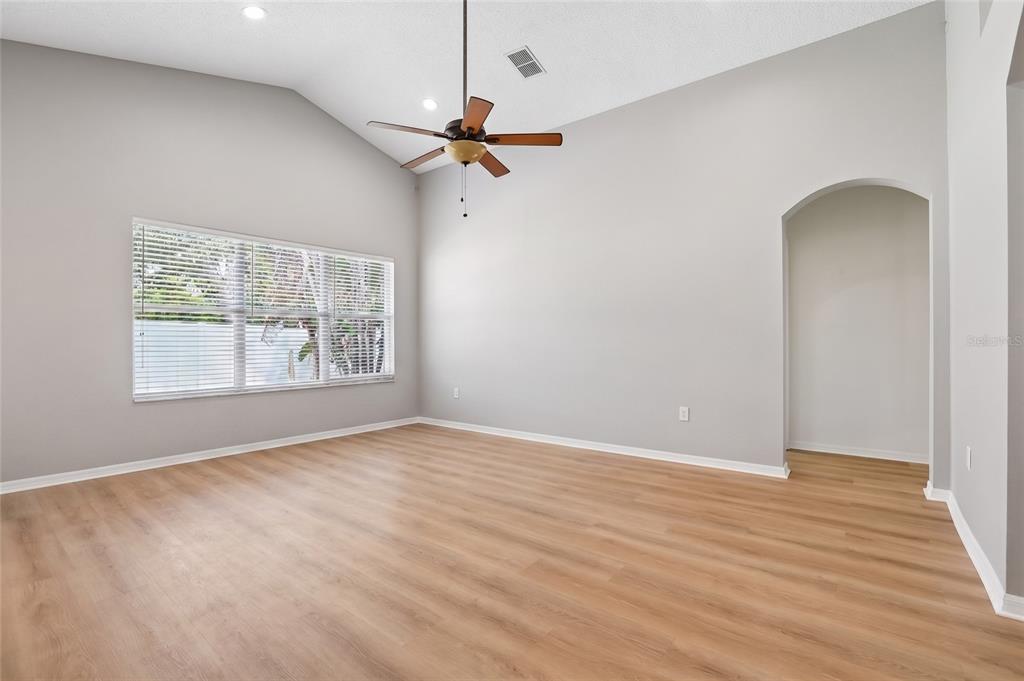 A spacious living room with vaulted ceilings, light wood flooring, and a ceiling fan — 2638 BIG PINE DRIVE, HOLIDAY, FL