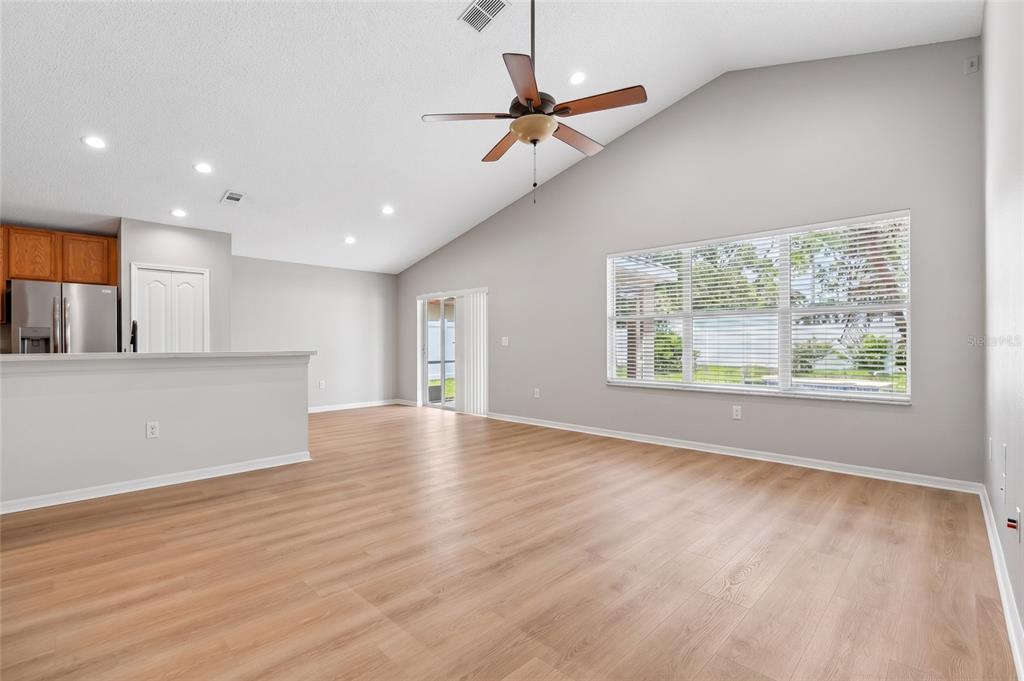 A living room with vaulted ceilings, light wood flooring, a sofa, and two leather armchairs — 2638 BIG PINE DRIVE, HOLIDAY, FL