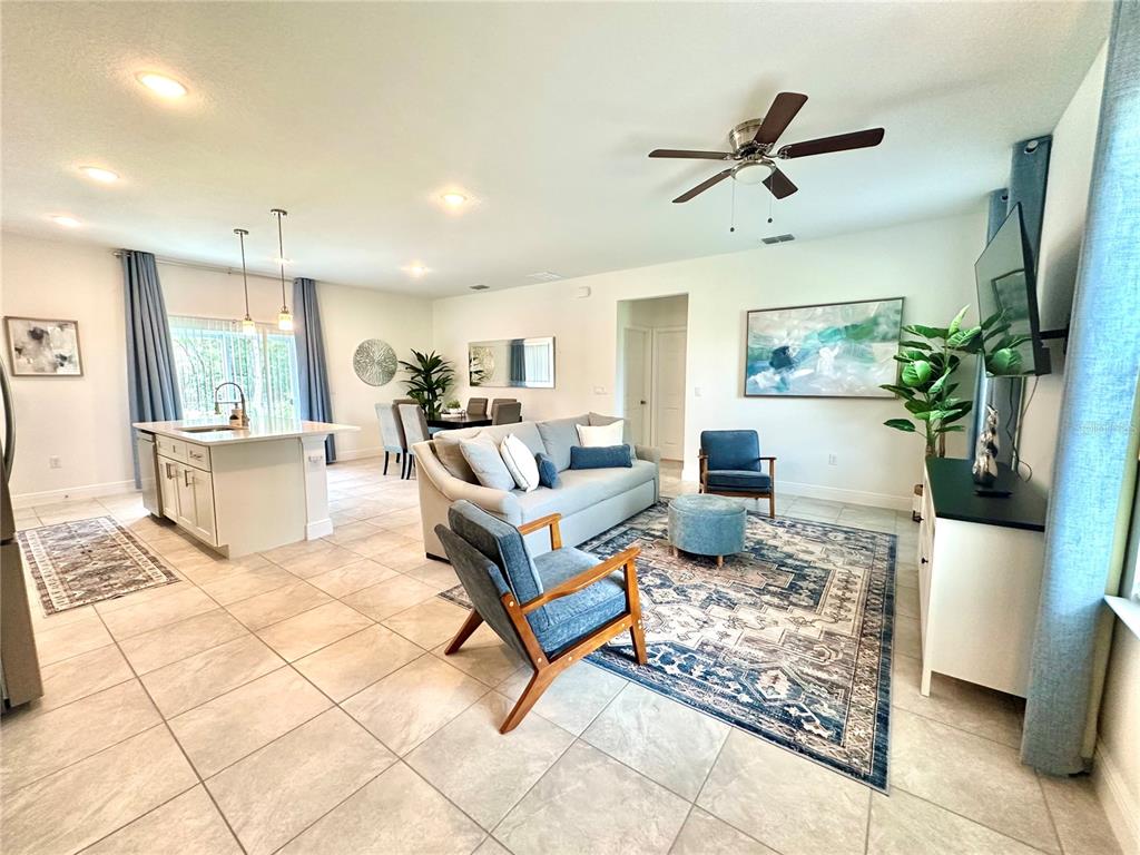 An open-concept living room and kitchen feature tile flooring, a ceiling fan, and blue accents — 6634 SW 151ST LOOP, OCALA, FL