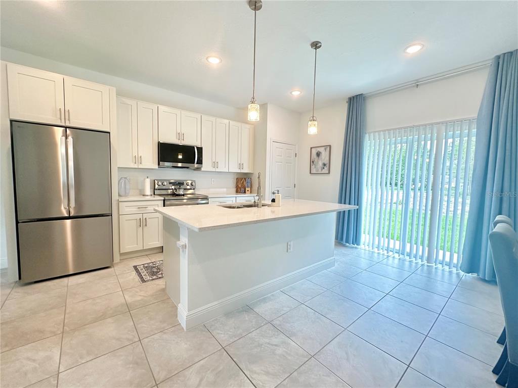 A kitchen with white cabinets, stainless steel appliances, a center island, and tile flooring — 6634 SW 151ST LOOP, OCALA, FL