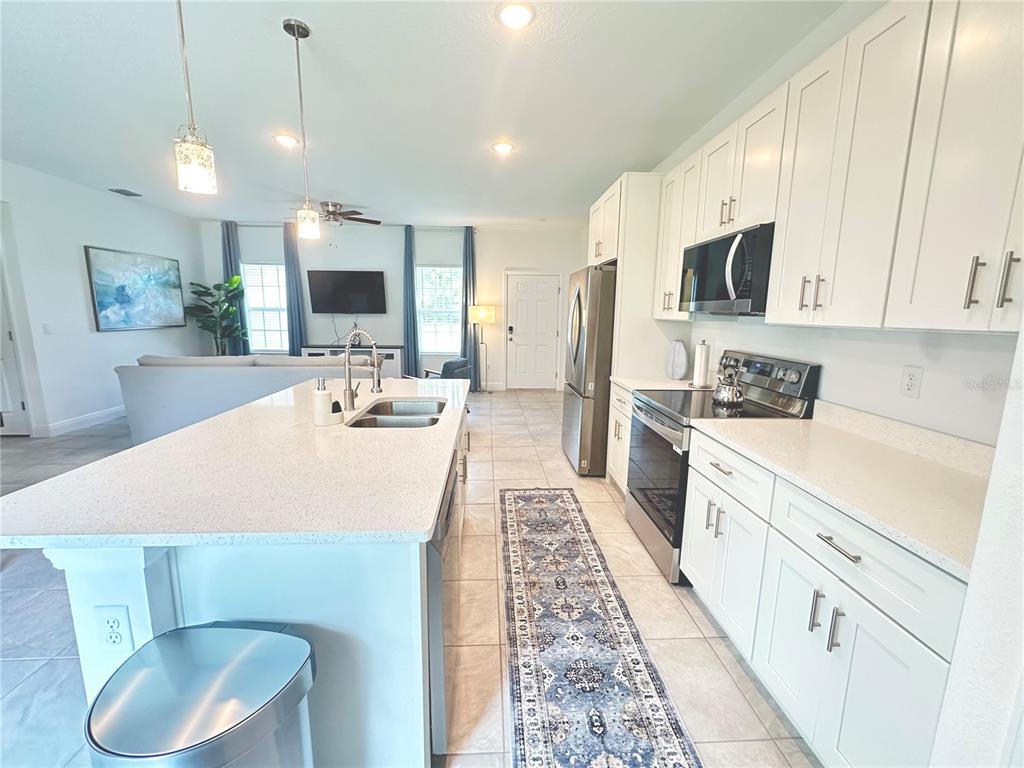 A kitchen with white cabinets and a quartz island overlooks an open-concept living area — 6634 SW 151ST LOOP, OCALA, FL