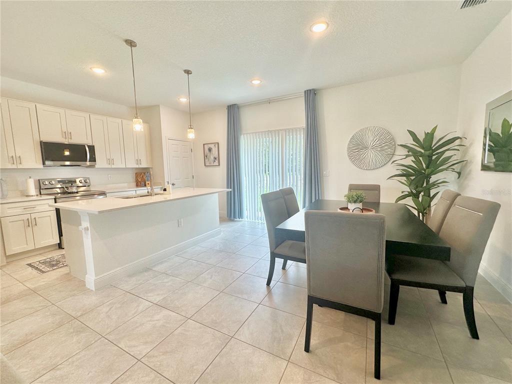 A kitchen with white cabinets and an island adjacent to a dining area with seating — 6634 SW 151ST LOOP, OCALA, FL