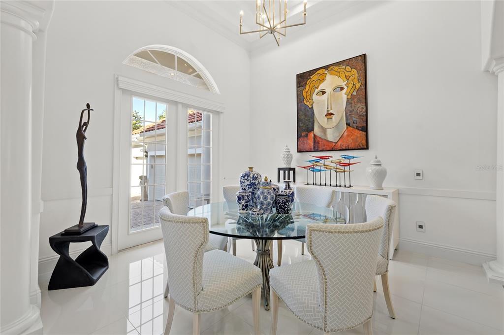 A dining room features a glass-topped table, upholstered chairs, a large painting, and glass doors — 11051 HAWKSHEAD COURT, WINDERMERE, FL