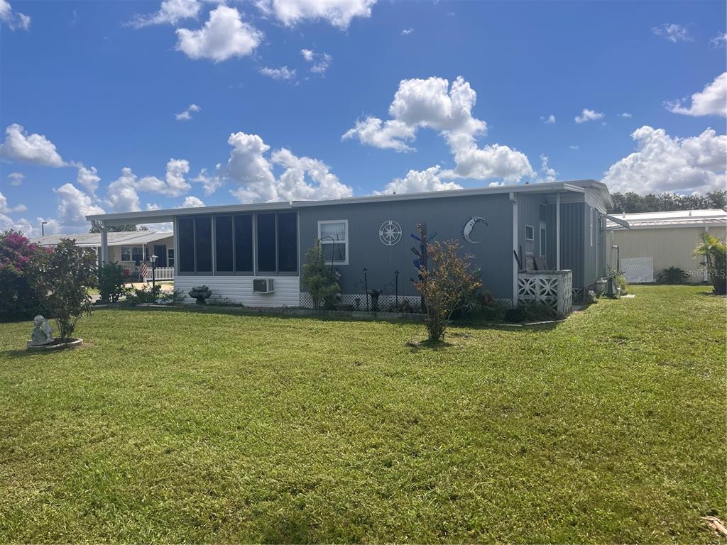 A single-story manufactured home with a screened-in porch sits on a grassy lot — 5316 53RD AVENUE E UNIT Q116, BRADENTON, FL