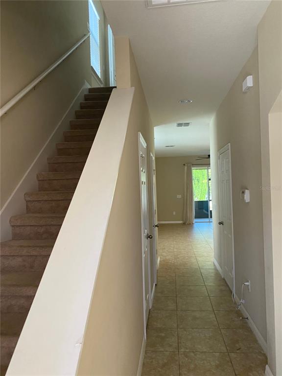 A carpeted staircase leads upstairs beside a tiled hallway with two closed white doors — 185 MITCHELL CREEK WAY, OVIEDO, FL