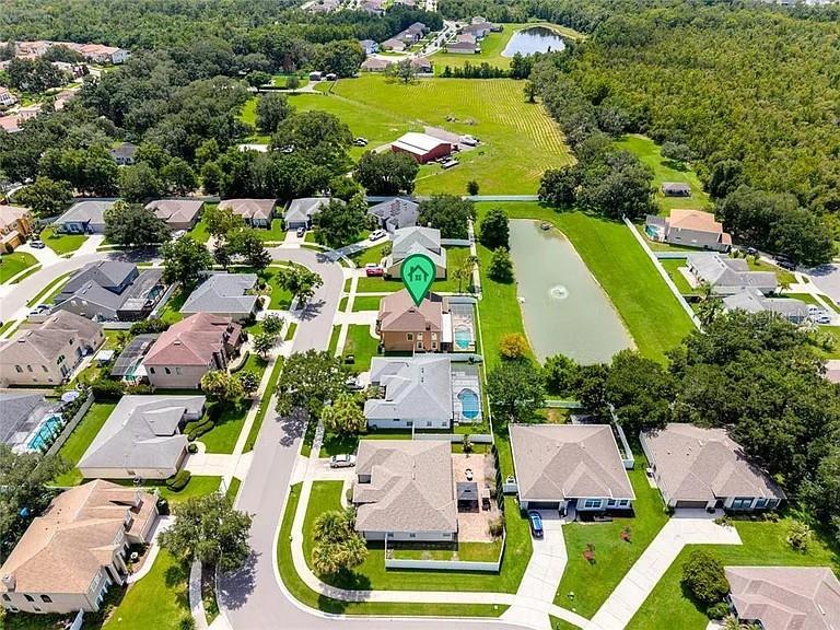 A swimming pool with a tiled water feature sits inside a screened-in patio enclosure — 353 LAKE AMBERLEIGH DRIVE, WINTER GARDEN, FL