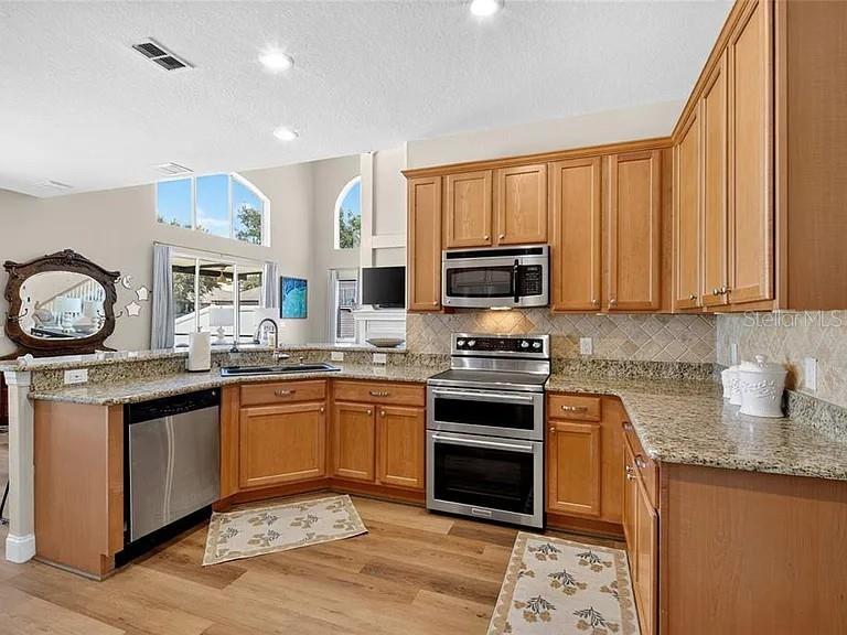 An empty room with beige walls, wood-look flooring, a ceiling fan, and two arched windows — 353 LAKE AMBERLEIGH DRIVE, WINTER GARDEN, FL