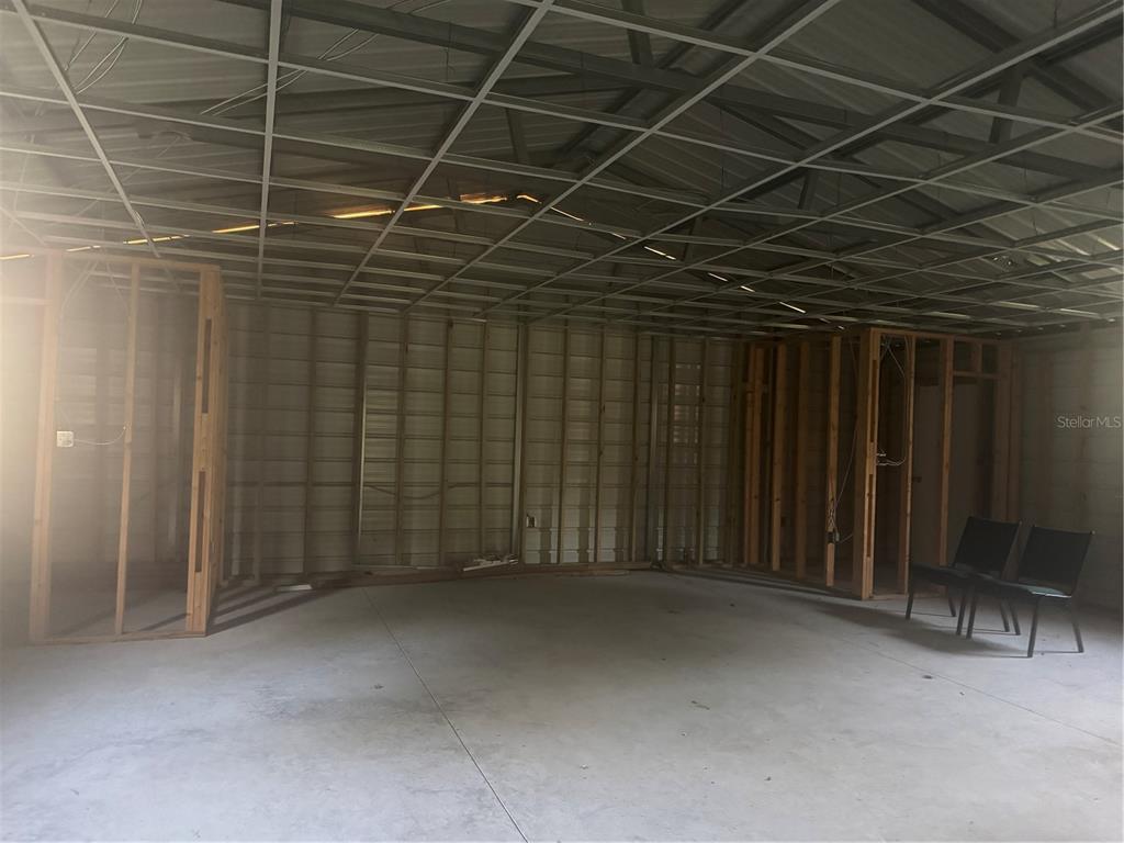 An unfinished room features exposed metal ceiling framing, wood wall studs, and a concrete floor — 7097 119TH ROAD, LIVE OAK, FL