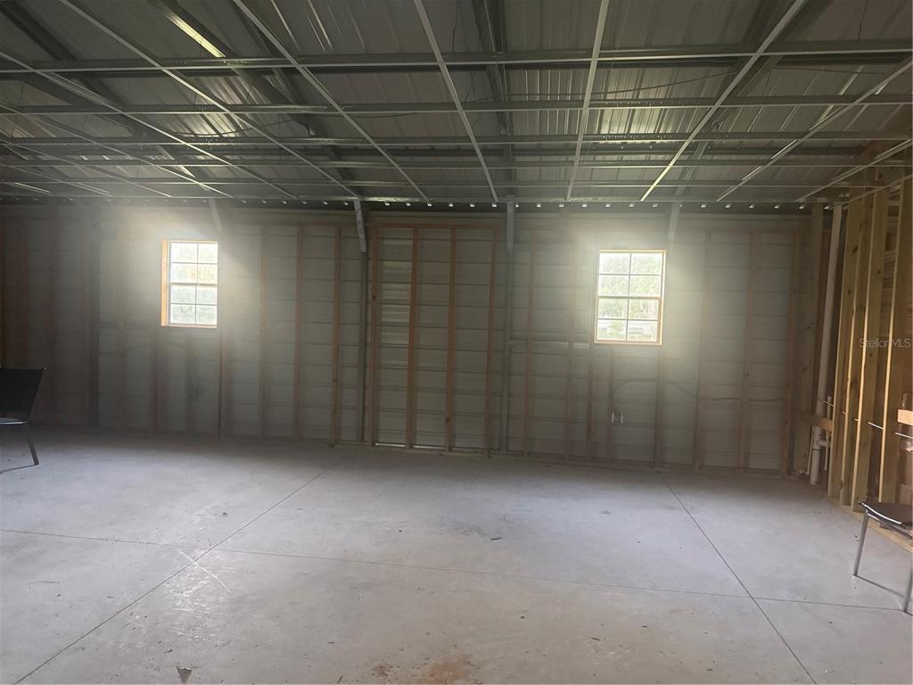 An unfinished room features exposed wall studs, a concrete floor, and two windows — 7097 119TH ROAD, LIVE OAK, FL