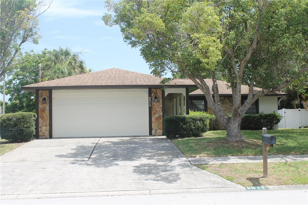 A single-story house with a stone facade, a two-car garage, and a large front tree — 8513 WINTER HAVEN DRIVE, HUDSON, FL