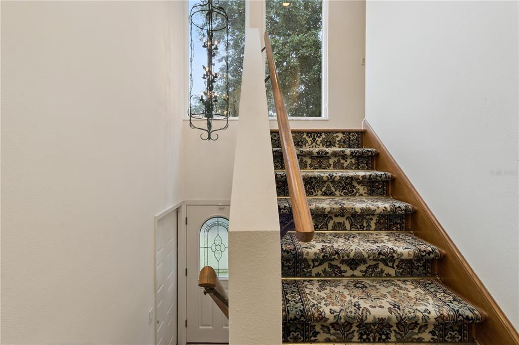 A staircase with patterned carpet and a wooden handrail leads to an upper landing — 75 SUNSET VIEW DRIVE UNIT 75, WINTER HAVEN, FL