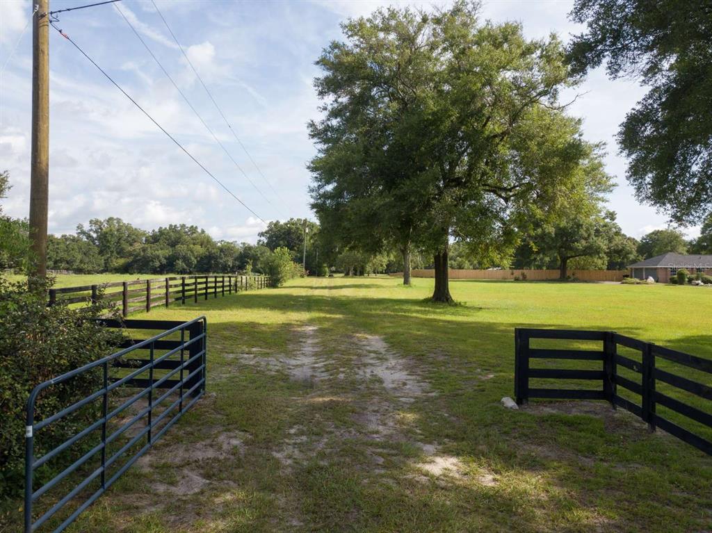 A dirt path leads through an open grassy field between two sections of black fencing — Lot 1 NW 94TH AVENUE, ALACHUA, FL